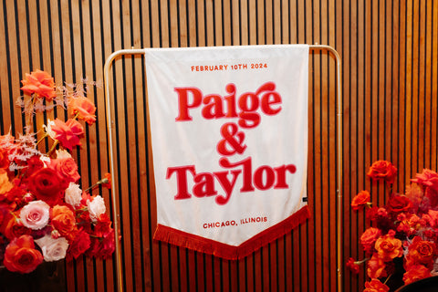 Close-up of wedding banner against wooden panel with floral decor.